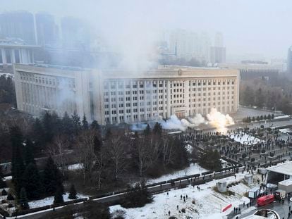 Columnas de humo se elevan ante un grupo de manifestantes junto al Ayuntamiento de Almaty (Kazajistán).