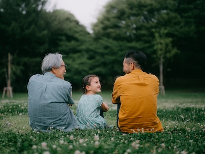 Una niña junto a su padre y a su abuelo en un parque.