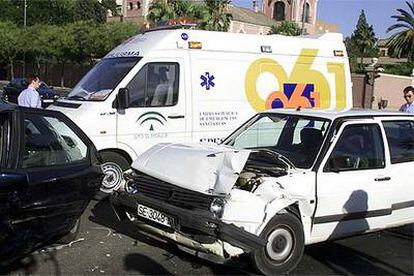 Una ambulancia, junto a dos coches accidentados en una avenida de Sevilla.