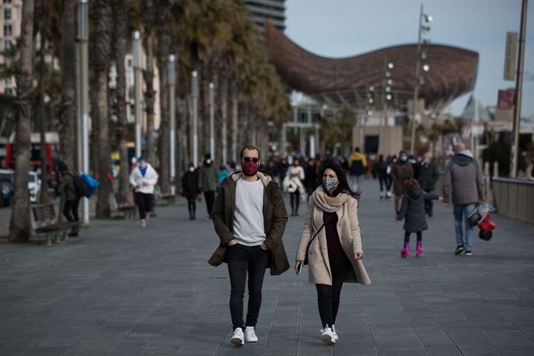 Varias personas protegidas con máscaras pasean por el paseo marítimo de Barcelona el 23 de enero.