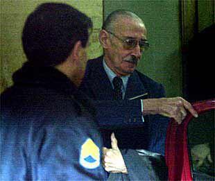 El ex dictador, Jorge Videla, junto a un policía, deja los tribunales de Buenos Aires tras ser interrogado.
