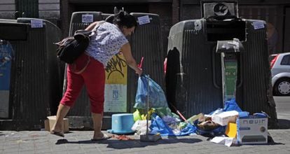 Una mujer deja una bolsa de basura en el suelo en Madrid.