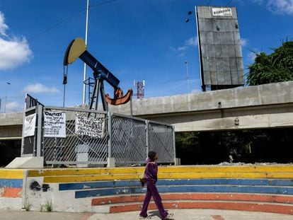 Una mujer camina en una plaza con una bomba de aceite en Caracas.
