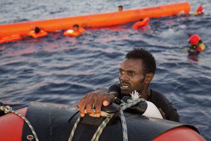 Un migrante eritreo se agarra a un bote salvavidas despu&eacute;s de haber saltado al agua desde una patera durante esta operaci&oacute;n de rescate, a 13 kil&oacute;metros al norte de Sabratha (Libia). 
