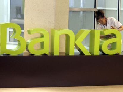 Una operaria limpia el logo de Bankia.