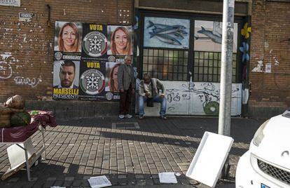 Dos inmigrantes ante los carteles electorale de la candidata fascista en Ostia.