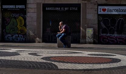Un home a la Rambla davant de botigues per a turistes.