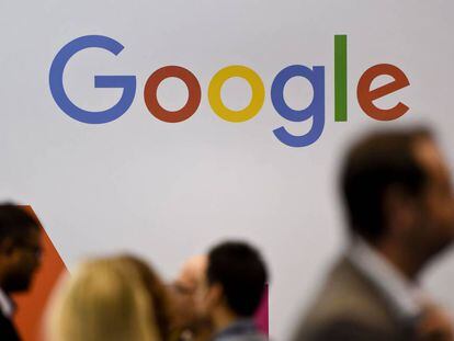 Personas pasan delante del logotipo de Google