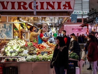 Varias personas compran en un puesto de fruta y verdura en el Mercado Central de Valencia.
