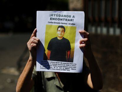 Una mujer sostiene un cartel de Carlos Santos, desaparecido desde enero de 2022.