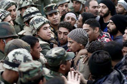 Manifestantes anti-Mursi tratan de romper el cordón de seguridad militar que rodea el palacio presidencial en El Cairo.