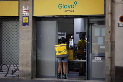 Un rider de Glovo frente a un supermercado express de la compañía de reparto a domicilio en Barcelona, en 2021.
