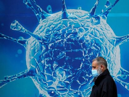 Un hombre con mascarilla pasa junto a una imagen del virus de la covid en Oldham (Reino Unido), el 3 agosto de 2020.
