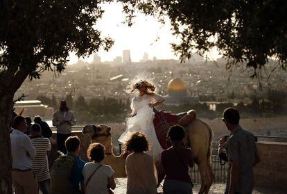 Una mujer junto a un camello es fotografiada en el Monte de los Olivos en Jerusalén.