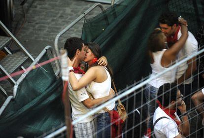 Dos parejas se besan mientras esperan a que empiece el cuarto encierro de las fiestas.