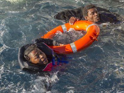 Dos inmigrantes que viajaban en las balsas hinchables son sacados del agua, a la que se lanzaron antes de ser rescatados.