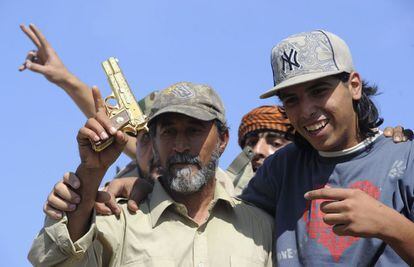 Un combatiente del CNT sostiene una pistola dorada, supuestamente perteneciente a Gadafi y que llevaba en el momento de ser apresado.