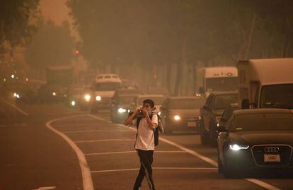 Un hombre se protege frente al humo en el condado de Orange (California). El fuerte viento complica las tareas de extinción y extiende el humo por las poblaciones aledañas al fuego.
