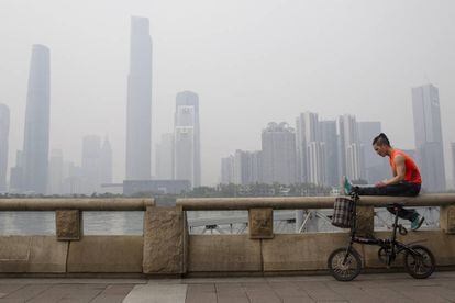 Un joven descansa a la orilla del r&iacute;o Perla cerca de un nuevo complejo de edificios comerciales y residenciales en Cant&oacute;n, China.