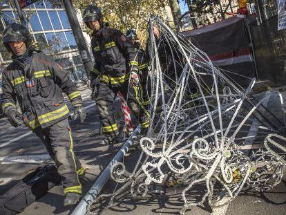 Los bomberos retiran las luces de Navidad desplomadas en el paseo de Gràcia.