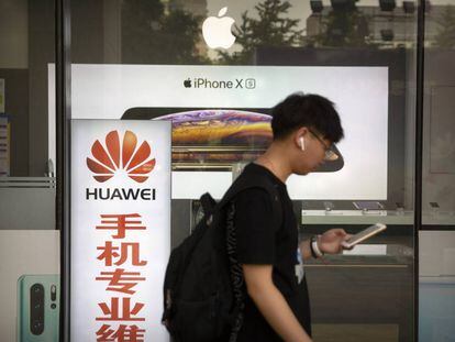 Un hombre camina junto a una tienda con anuncios de Huawei y Apple, en Pekín, el pasado viernes.
