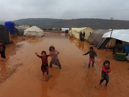 Niños sirios junto a las tiendas de un campamento de refugiados inundado, el domingo en Idlib.