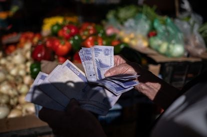 Un mujer cuenta bolívares para realizar compras en un mercado de Caracas.