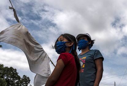 Una mujer y su hija se encuentran en una carretera con una bandera blanca improvisada pidiendo comida durante la cuarentena obligatoria decretada por el gobierno contra la propagación de la covid-19 en San Luis Talpa, El Salvador, el 29 de mayo de 2020.