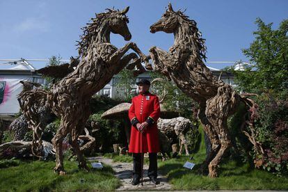 Un veterano de Chelsea posa frente a las esculturas Driftwood de James Doran Webb en el Chelsea Flower Show.
