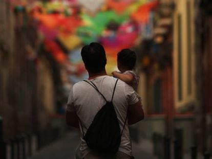 Un hombre pasea con su hijo en brazos por una calle adornada de Madrid.