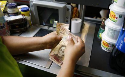 Una cajera cuenta dinero en un súper de Caracas.