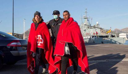 Un agente de policía acompaña a dos inmigrantes que han sido rescatados en aguas murcianas.