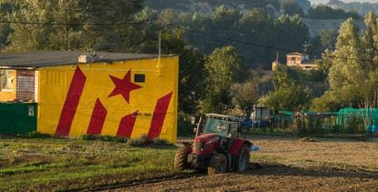 Un agricultor con un tractor ante una fachada que tiene pintada una &#039;estelada&#039;