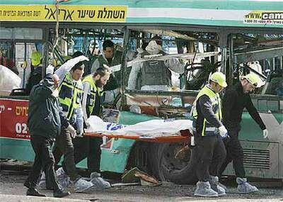 Personal sanitario traslada un cadáver delante del autobús en el que se inmoló el suicida palestino.