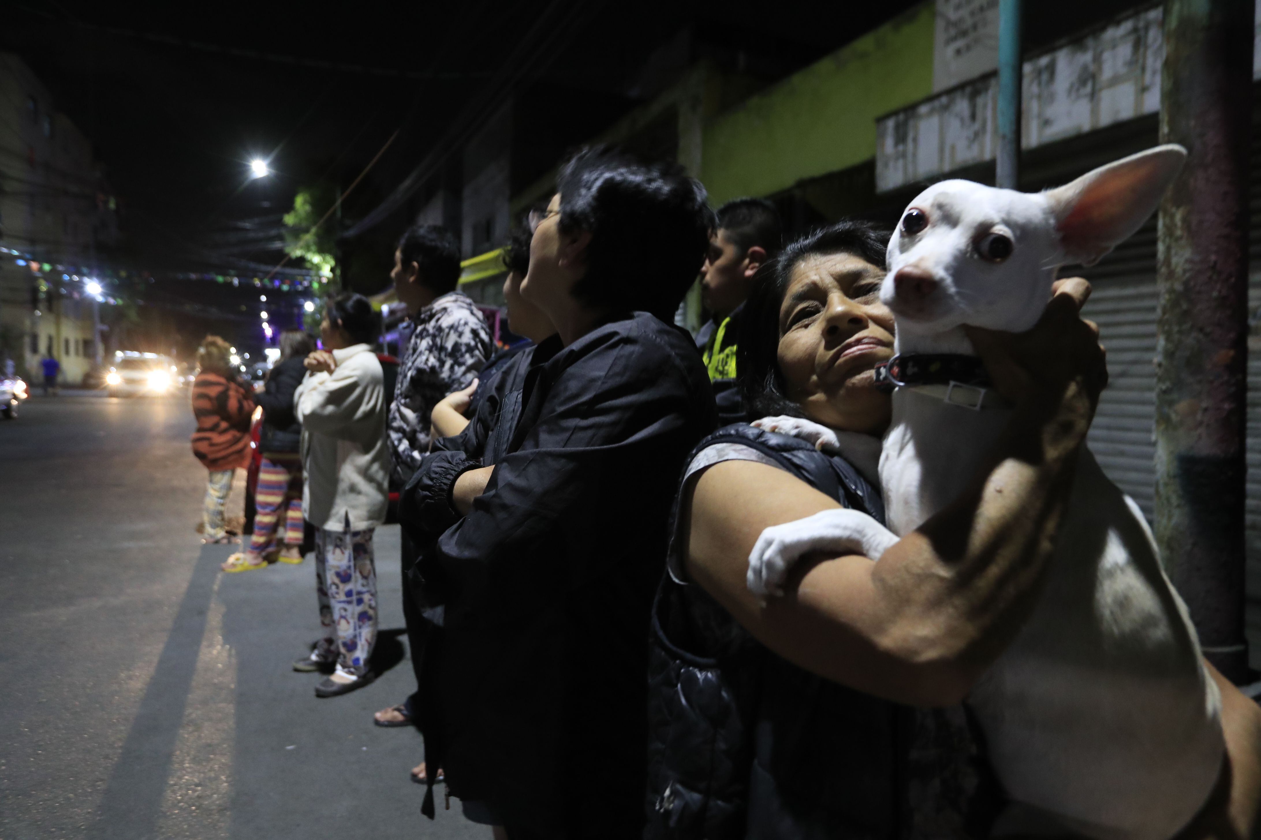 Una mujer sostiene a su mascota después de evacuar su vivienda la noche del 18 de abril, durante un sismo.