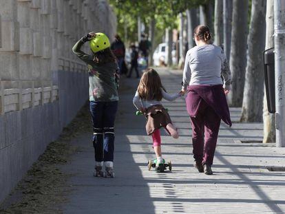 Una mujer pasea con dos niñas en los alrededores de un parque de Madrid.