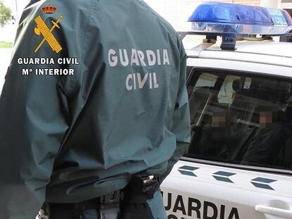 Un agente de la Guardia Civil junto a un coche patrulla.