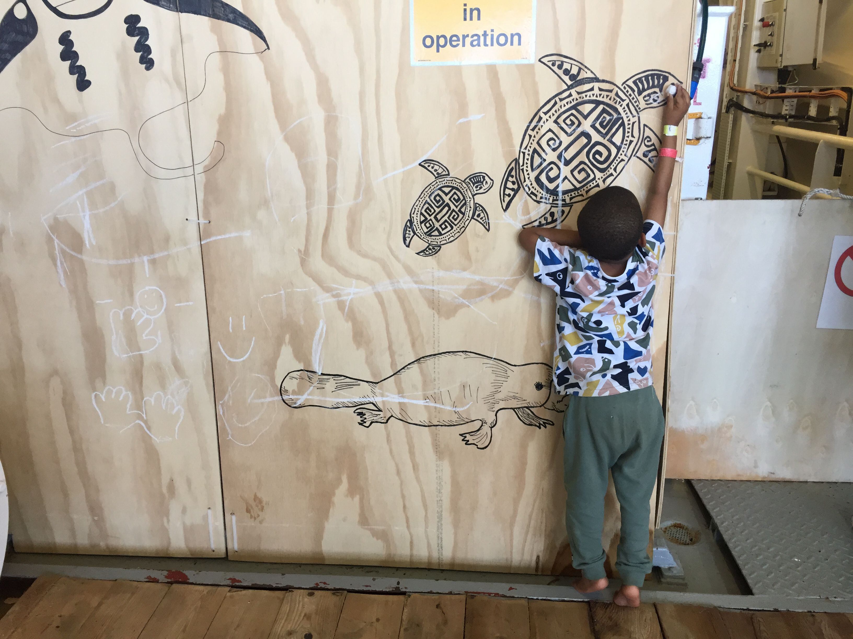 Aiman, de 3 años, pinta con una tiza en un tablerillo decorado con animales en la cubierta de mujeres.