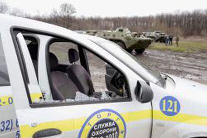 Un veh&iacute;culo da&ntilde;ado en Slaviansk, tras los choques armados entre activistas prorrusos y soldados ucranianos (al fondo).