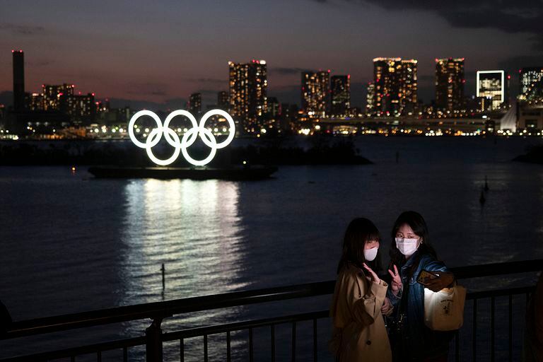 Dos jóvenes se hacen un selfie ante los anillos olímpicos en Tokio.