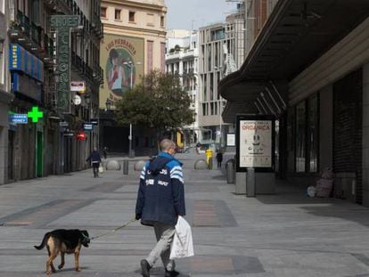 Un hombre pasea a su perro por la céntrica calle de Preciados.
