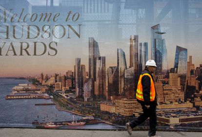 Un obrero pasa por delante de un cartel promocional del nuevo barrio gentrificado de Nueva York, Hudson Yards. |