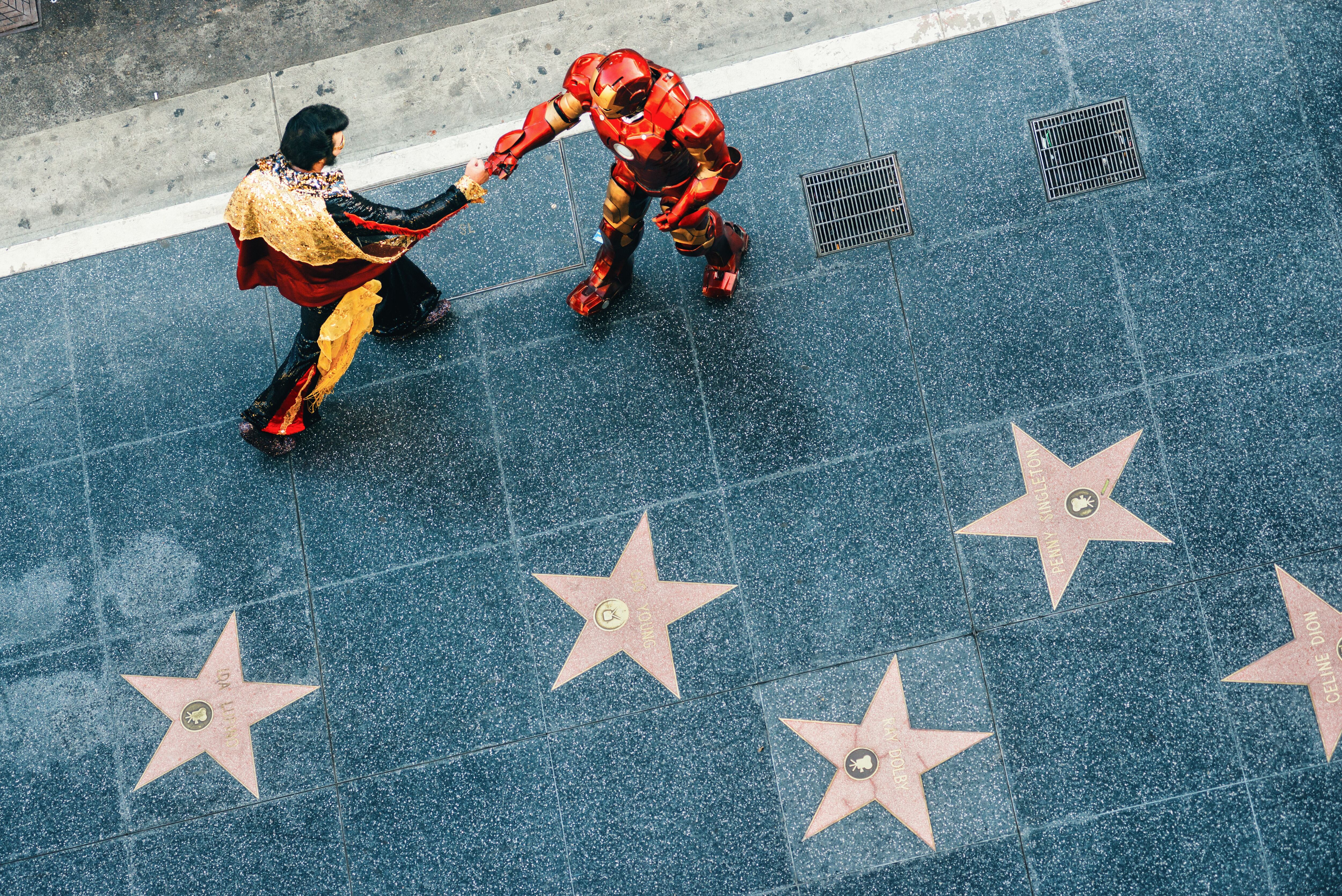 Dos personas disfrazadas de Ironman y Elvis Presley se dan la mano en el paseo de la Fama de Hollywood. 