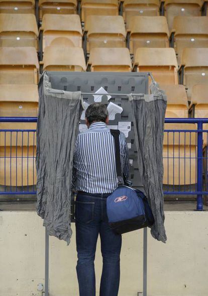 Un hombre escoge papeleta en un colegio electoral del País Vasco.