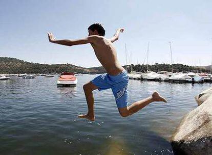 Un adolescente salta al agua sucia del puerto deportivo situado en el pantano de San Juan.