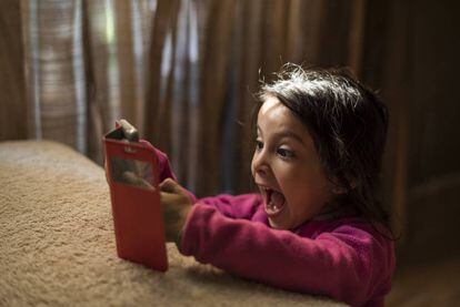 Una niña mira emocionada un móvil.