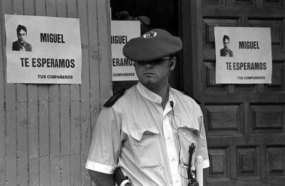 Un ertzantza monta guardia en el domicilio del concejal secuestrado por ETA. Los carteles, con la fotografía de Miguel Ángel, rezan: "Te esperamos".