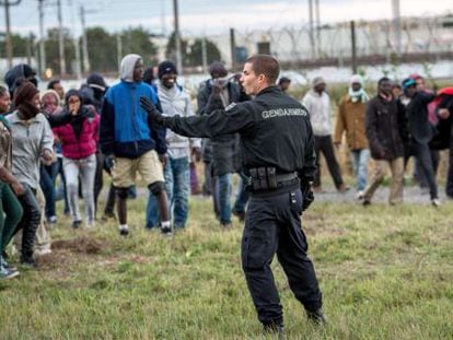 Un gendarme ante un grupo de migrantes en Calais.