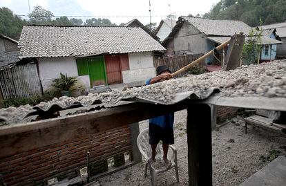 Un hombre limpia el techo de su casa, cubierto de piedras, en la aldea de Mbladak en Blitar tras ser lanzadas durante la erupción del volcán Kelud en Indonesia, 14 de febrero de 2014.