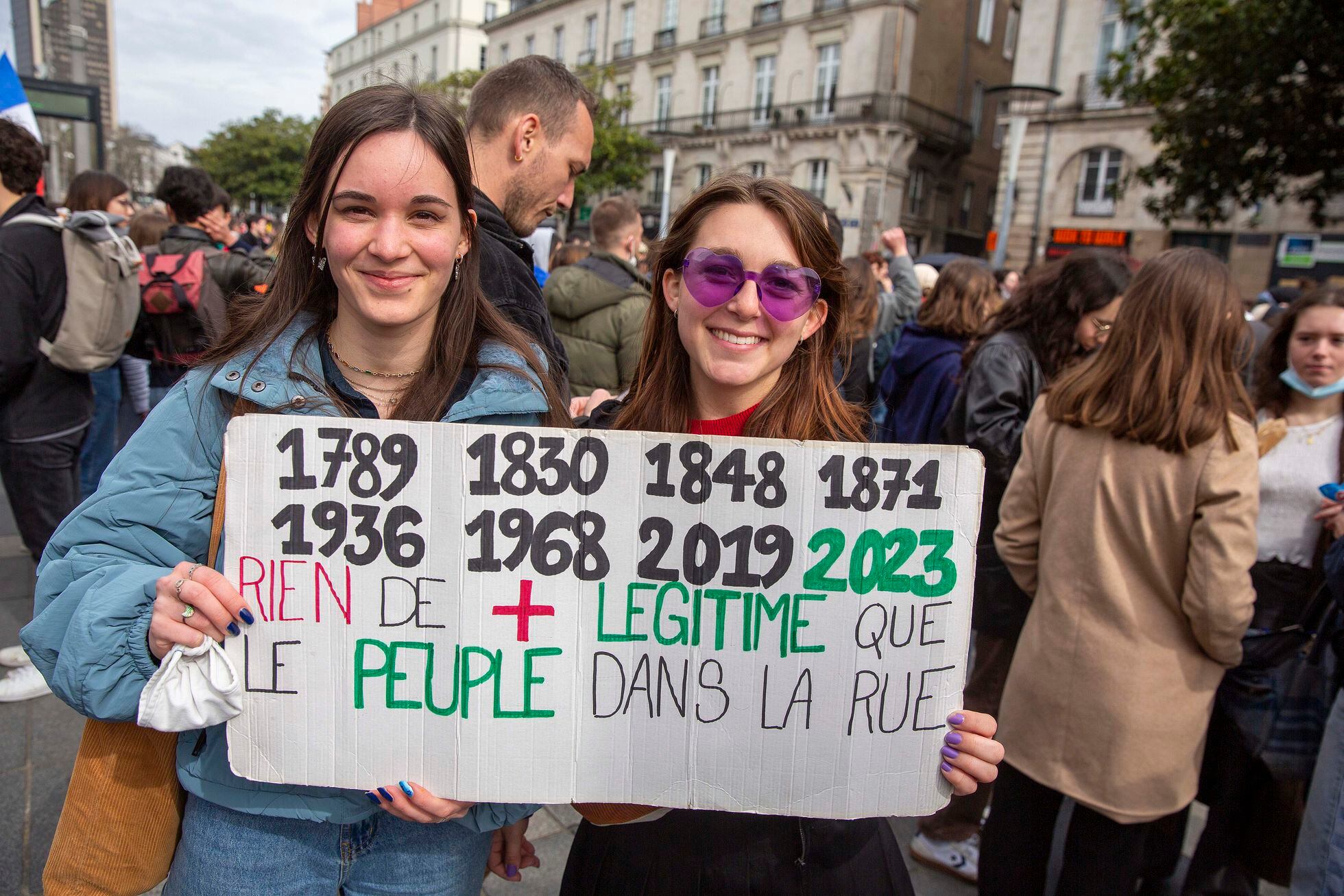Adèle Gratadon, a la izquierda, junto a su amiga Lola Pierre de Ming, portan una pancarta en la que han apuntado todas las protestas históricas de Francia, desde la Revolución Francesa. El texto dice: "No hay nada más legítimo que el pueblo en la calle". 